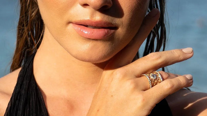 Une jeune femme dos à la mer porte une bague écaille avec des diamants